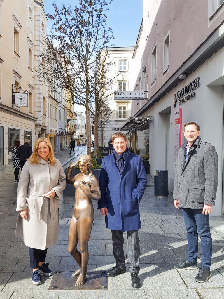 Bürgermeister Dr. Andreas Rabl, Vizebürgermeisterin Christa Raggl-Mühlberger und Robert Reif, Regionaldirektor Sparkasse Wels stehen in der Schmidtgasse neben der neuen Bronzestatue der Venus