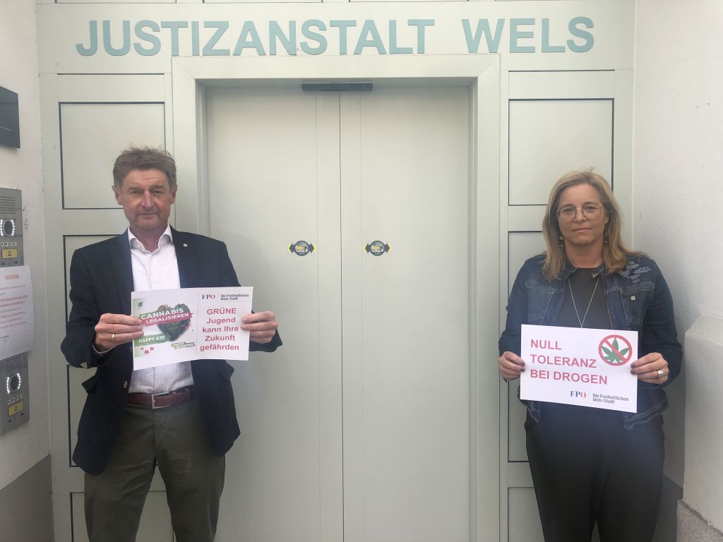 Gerhard Kroiß und Christa Raggl-Mühlberger stehen vor der Tür der Justizanstalt Wels mit Hinweisschildern 