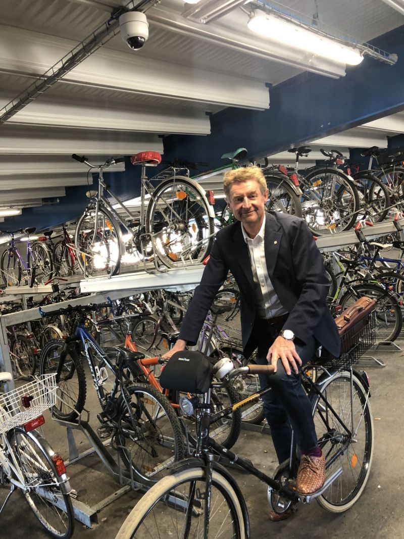 vzbgm. Gerhard Kroiß sitz auf seinem Fahrrad in der Fahrrad-Parkgarage am Welser ÖBB Parkdeck. Über ihm zu sehen ist die neue Videoüberwachung
