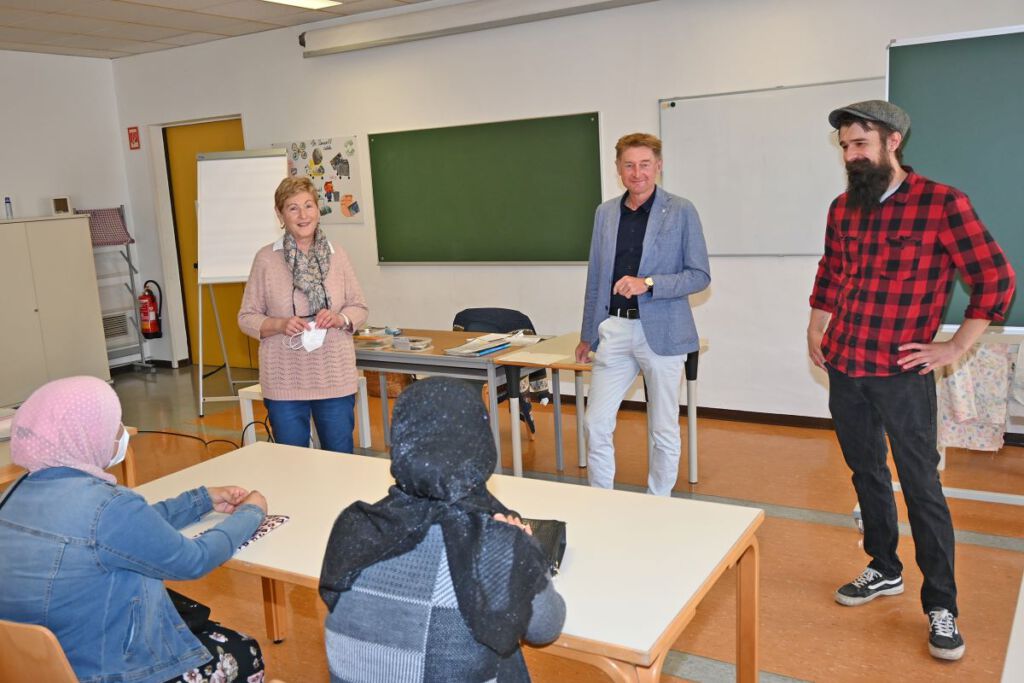 Vizebürgermeister und Integrationsreferent Gerhard Kroiß steht mit der Trainerin und einem Mitarbeiter der Volkshilfe im Unterrichtsraum, vor Ihnen sitzen 2 Kursteilnehmerinnen