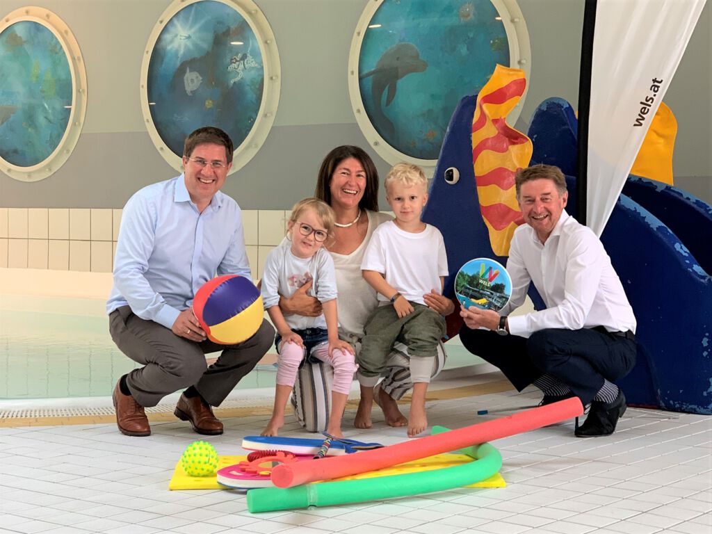 Bürgermeister Dr. Andreas Rabl und Sportreferent Vzbgm. Gerhard Kroiß mit der Schwimmtrainerin und 2 Kindern vor dem Schwimmbecken im Welser Hallenbad