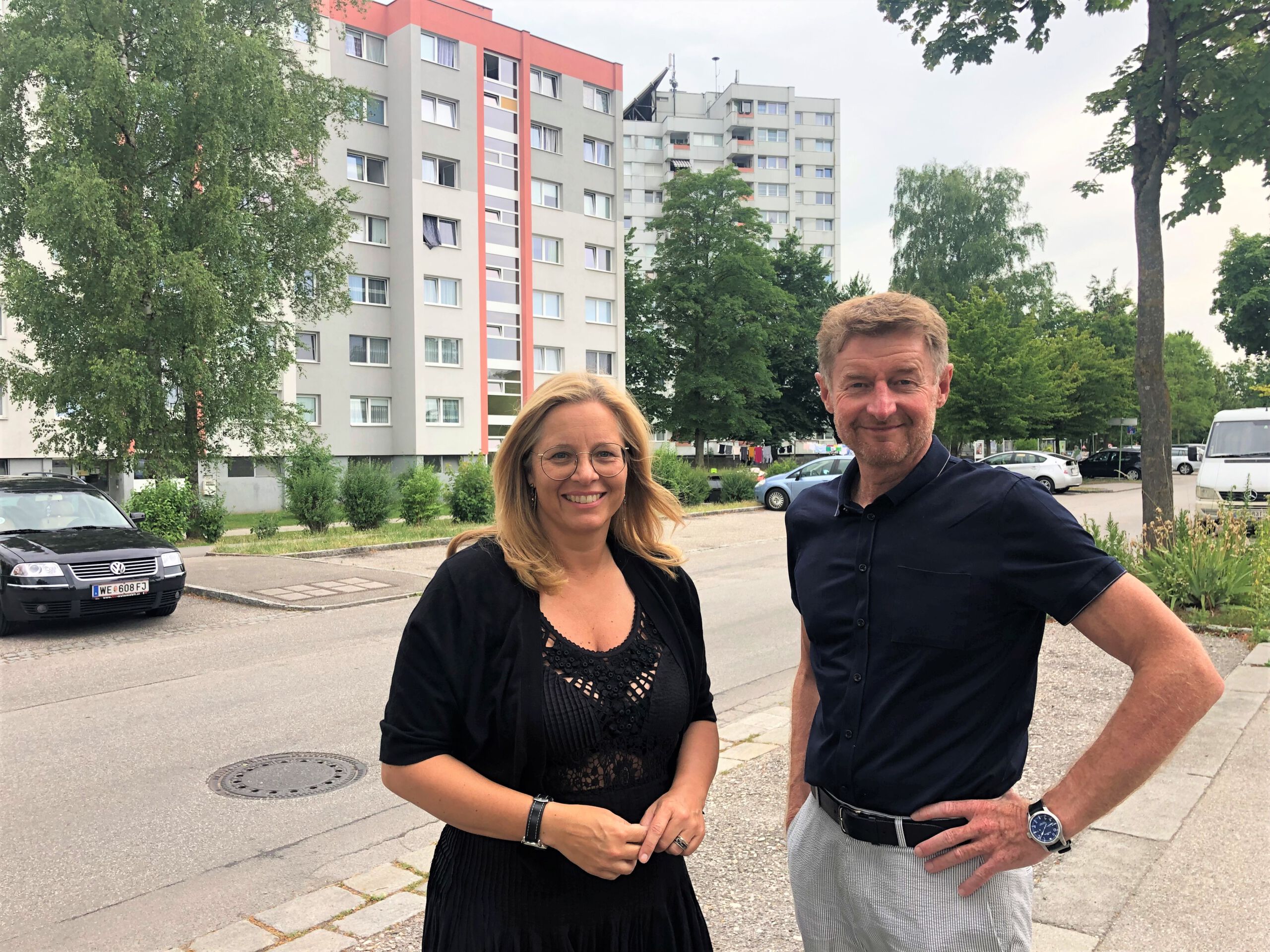 Vzbgm. Gerhard Kroiß und Vzbgm. Christa Raggl-Mühlberger stehen vor Hochhäusern in der Noitzmühle