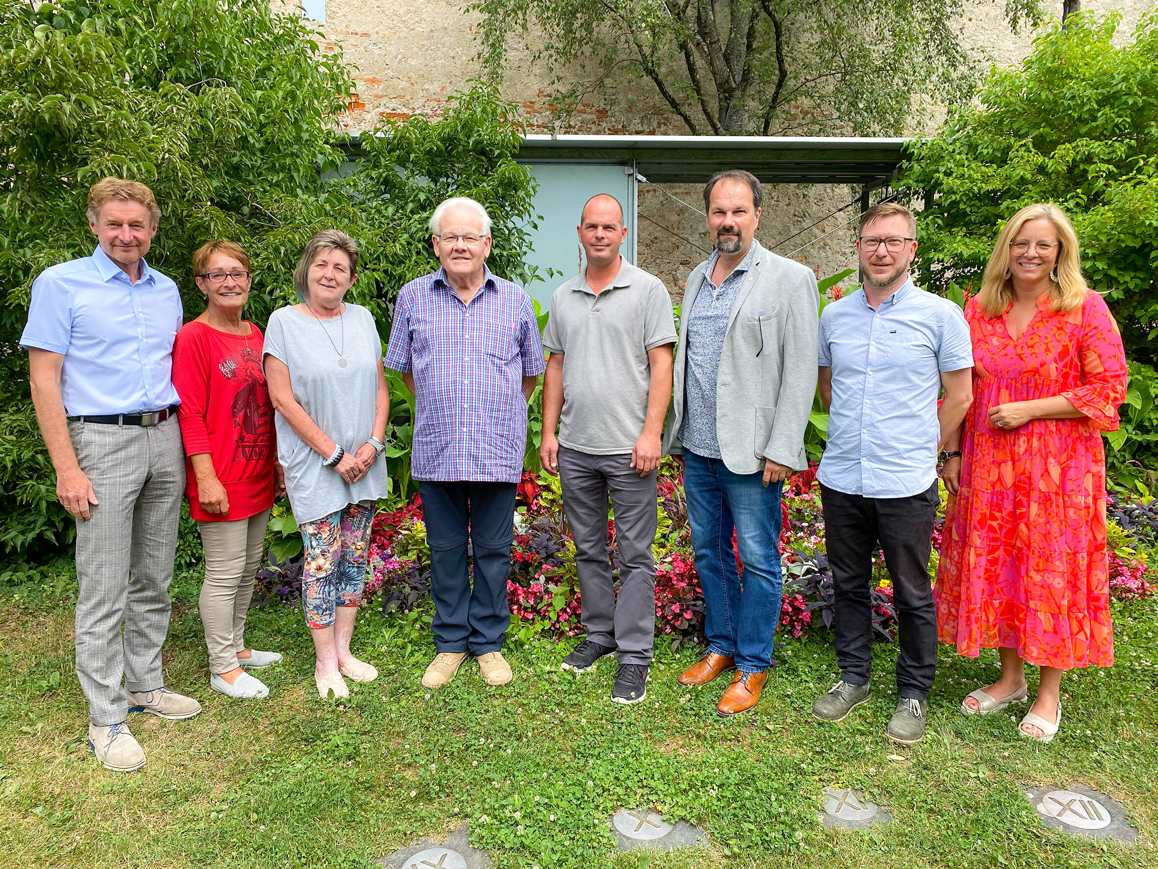 Die beiden Referenten stehen gemeinsam mit den Nachbarschaftssprechern und den Mitarbeitern von Wohnen im Dialog und der Welser Heimstätte auf einer Wiese