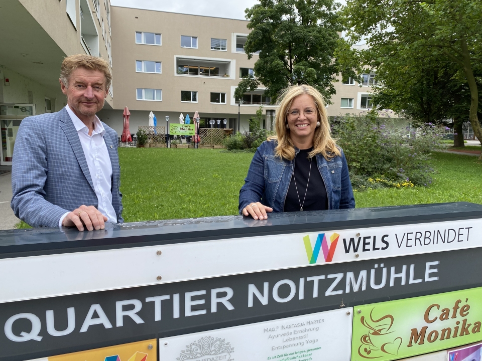 Herr Vizebürgermeister Kroiß und Frau Vizebürgermeister Raggl-Mühlberger stehen in der Noitzmühle hinter dem Schild 