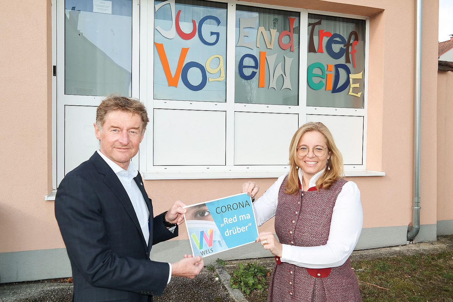 Die beiden Vizebürgermeister Gerhard Kroiß und Christa Raggl-Mühlberger stehen vor dem Jugendtreff Vogelweide mit einem Schild, welches die Aufschrift trägt