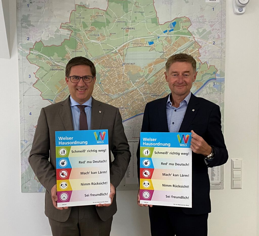 Bürgermeister Dr. Rabl und Vizebürgermeister Kroiß mit der Welser Hausordnung vor der Wels-Landkarte